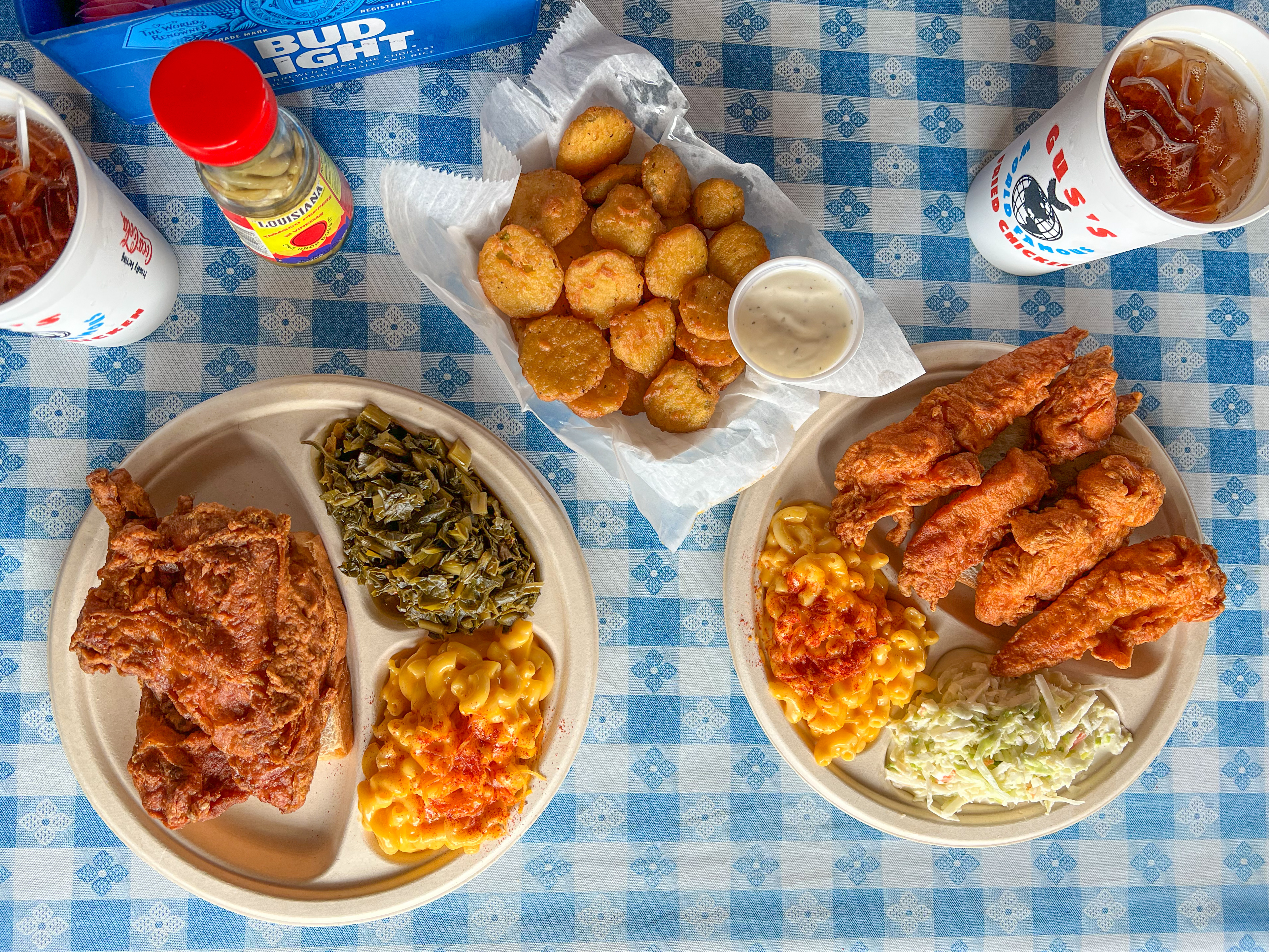 photo of plates of food from gus fried chicken: fried chicken, Mac n cheese, fried pickles and coleslaw