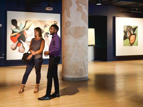 Two people stand looking at pieces in Crosstown Concourse art gallery.
