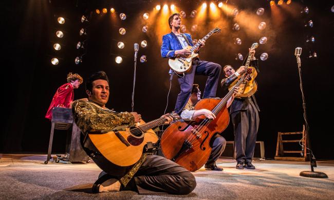 Performers on stage with guitars in a play at Playhouse on the Square.