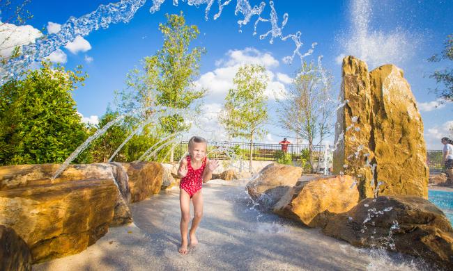 A girl runs through the rock splash and spray features at Shelby Farms Park's splash pad.