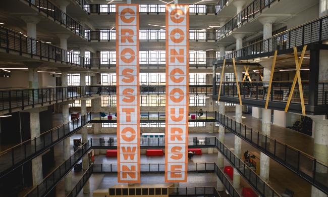 interior shot that shows multiple floors of crosstown concourse with orange and white hanging banners that say Crosstown Concourse.