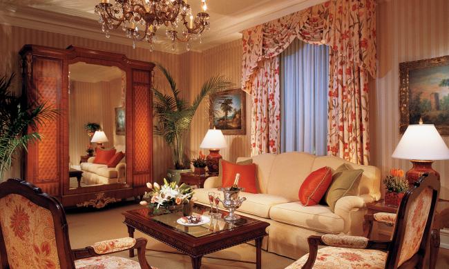 Red and white decor with a couch, chairs, wardrobe, chandelier and more inside the Celebrity Suite of The Peabody Memphis.