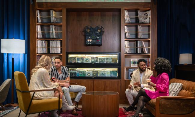 Friends gathered in the lobby of Central Station Memphis with vinyl records lining shelves behind them.