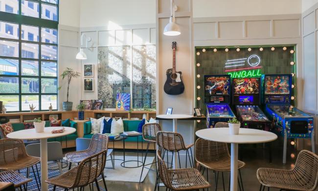 Inside the lobby of Moxy Memphis Downtown with pinball machines, seating and music-themed decor.