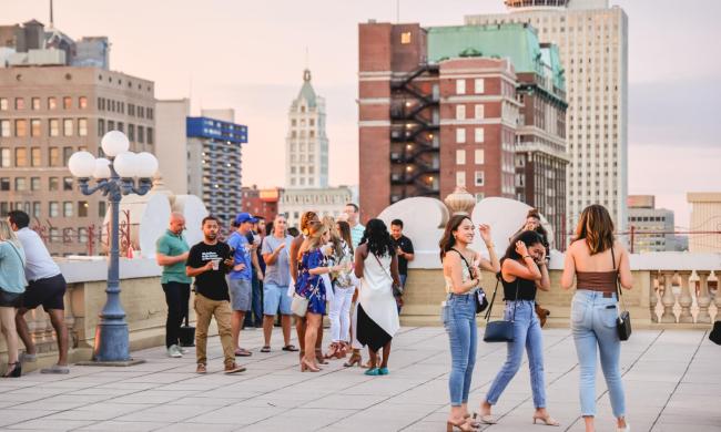 People gathering on the rooftop of The Peabody Memphis with views of other downtown Memphis buildings in the background.