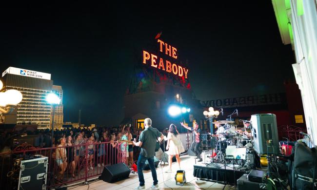 Band playing in front of a crowd at the Rooftop Party at The Peabody.
