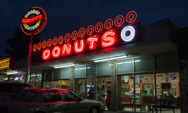 Exterior of Gibson's Donuts with the red neon sign on above the entrance.