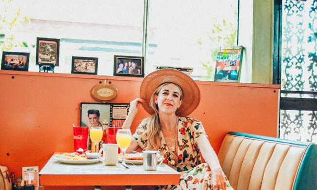 A woman sitting in a booth with a table full of food at The Arcade Restaurant.
