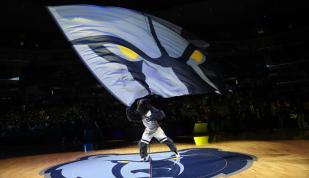 Grizz waving Memphis Grizzlies flag at an NBA basketball game.