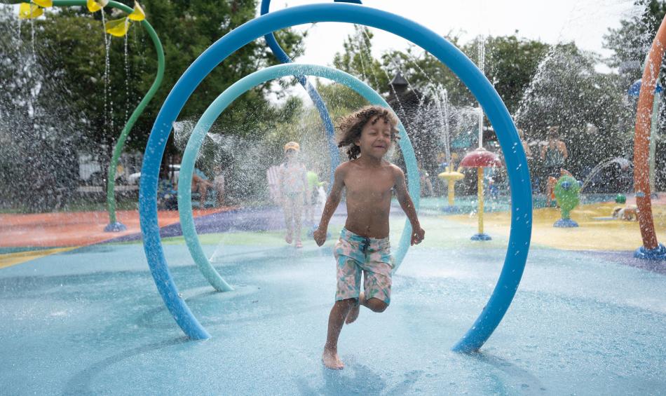 Child running through the sprinklers on the splash pad at Children's Museum of Memphis.