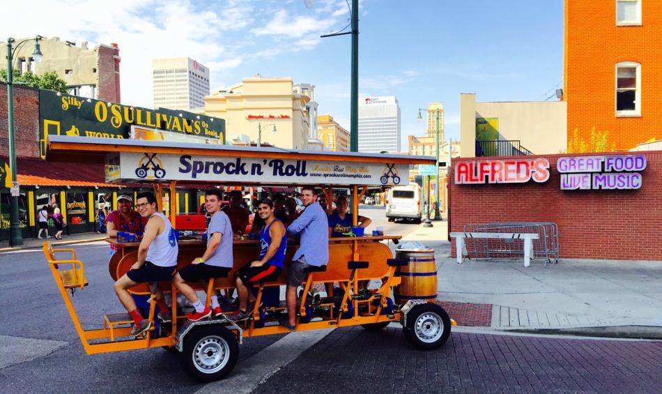 A Sprock 'n' Roll cart (a marigold, multi-passenger bike) rolls through downtown Memphis.